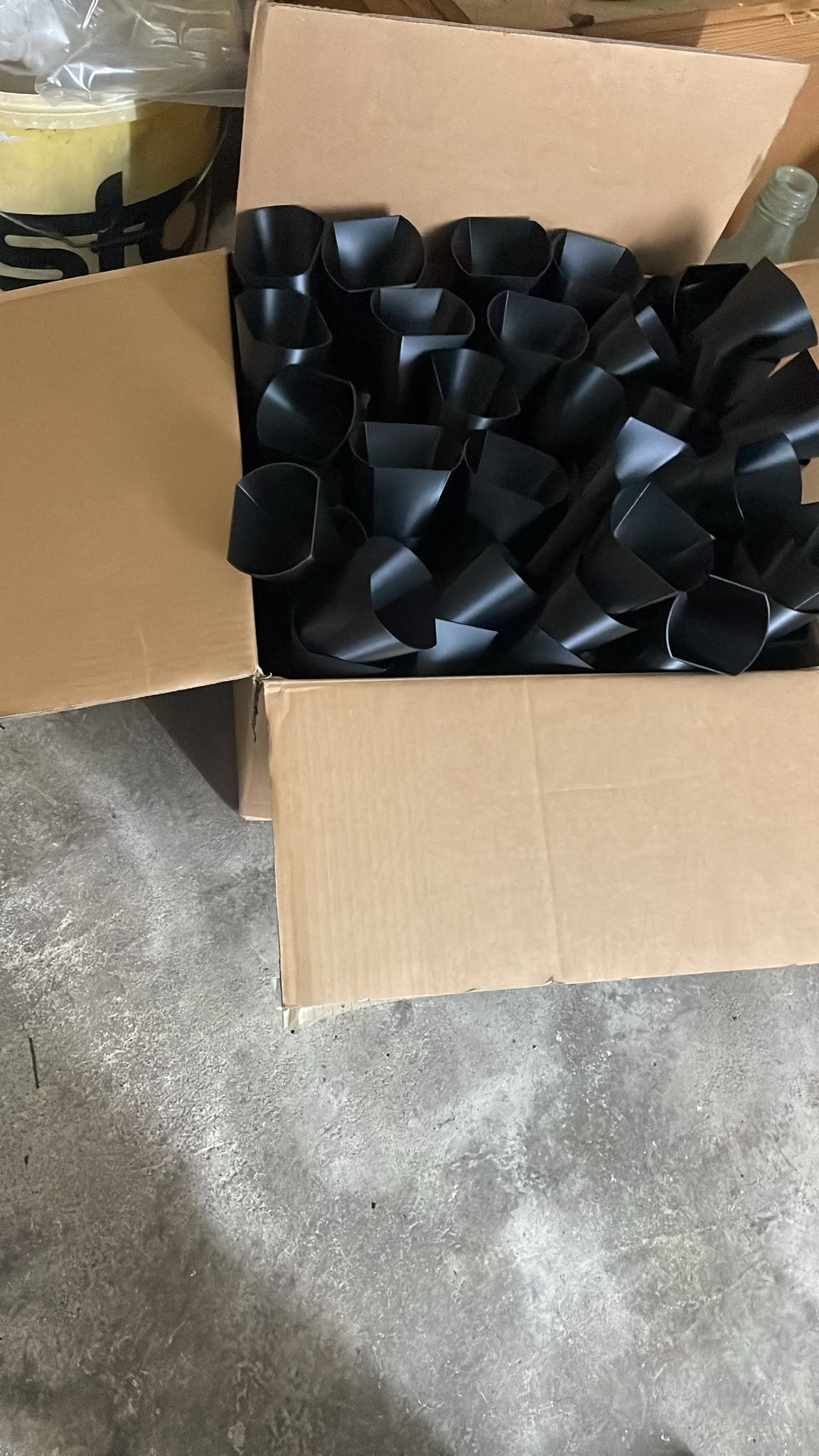Fertig produzierte schwarze Kunststoff-Serienteile von LEXOS in einem Versandkarton